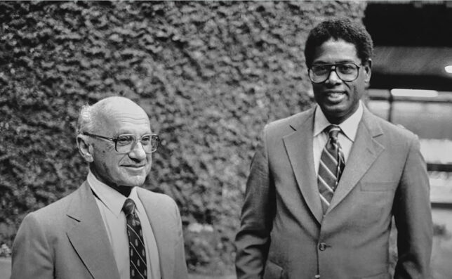 Milton Friedman and Thomas Sowell standing together in a black and white photograph.