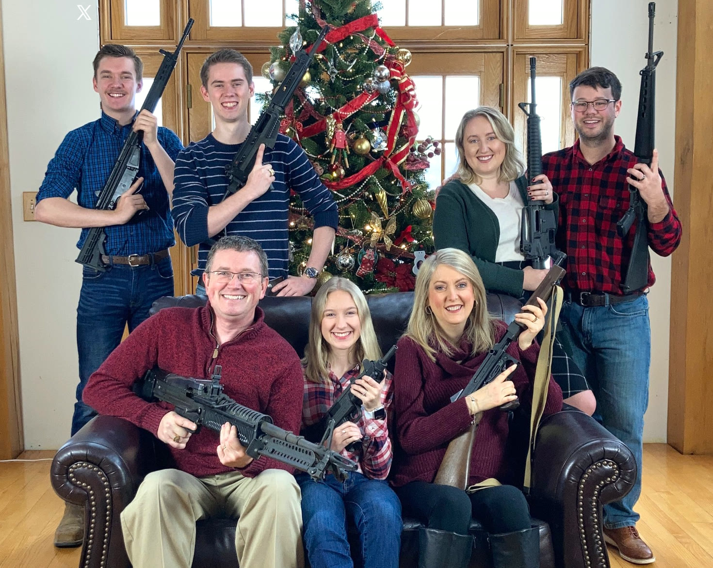 The Massie family posing with rifles in front of the Christmas tree.